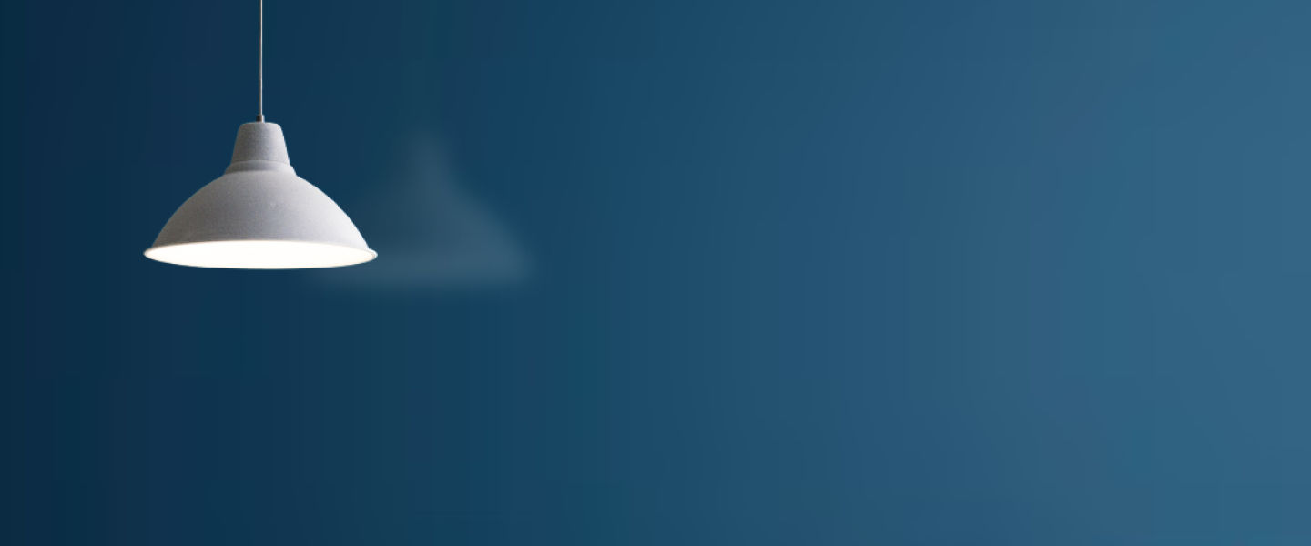 Blue background with a simple white funnel shaped lamp hanging